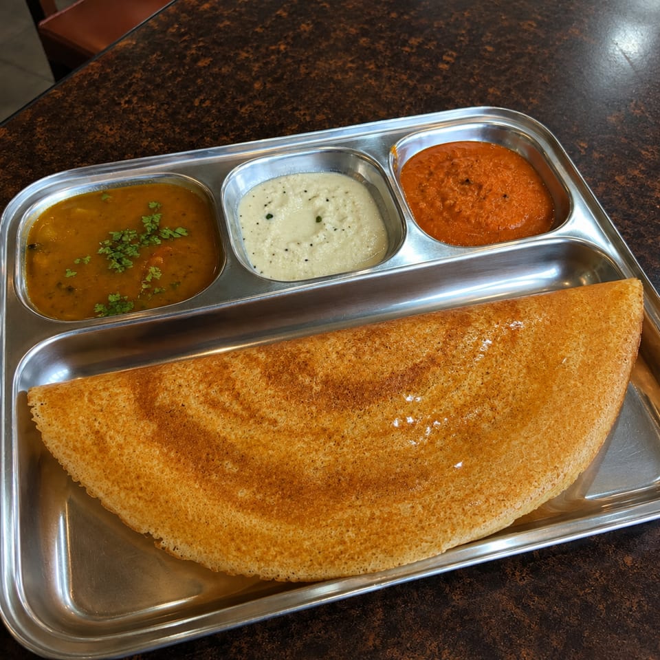 Crispy folded dosa served on a stainless-steel tray with sambar, coconut chutney, and tomato chutney.