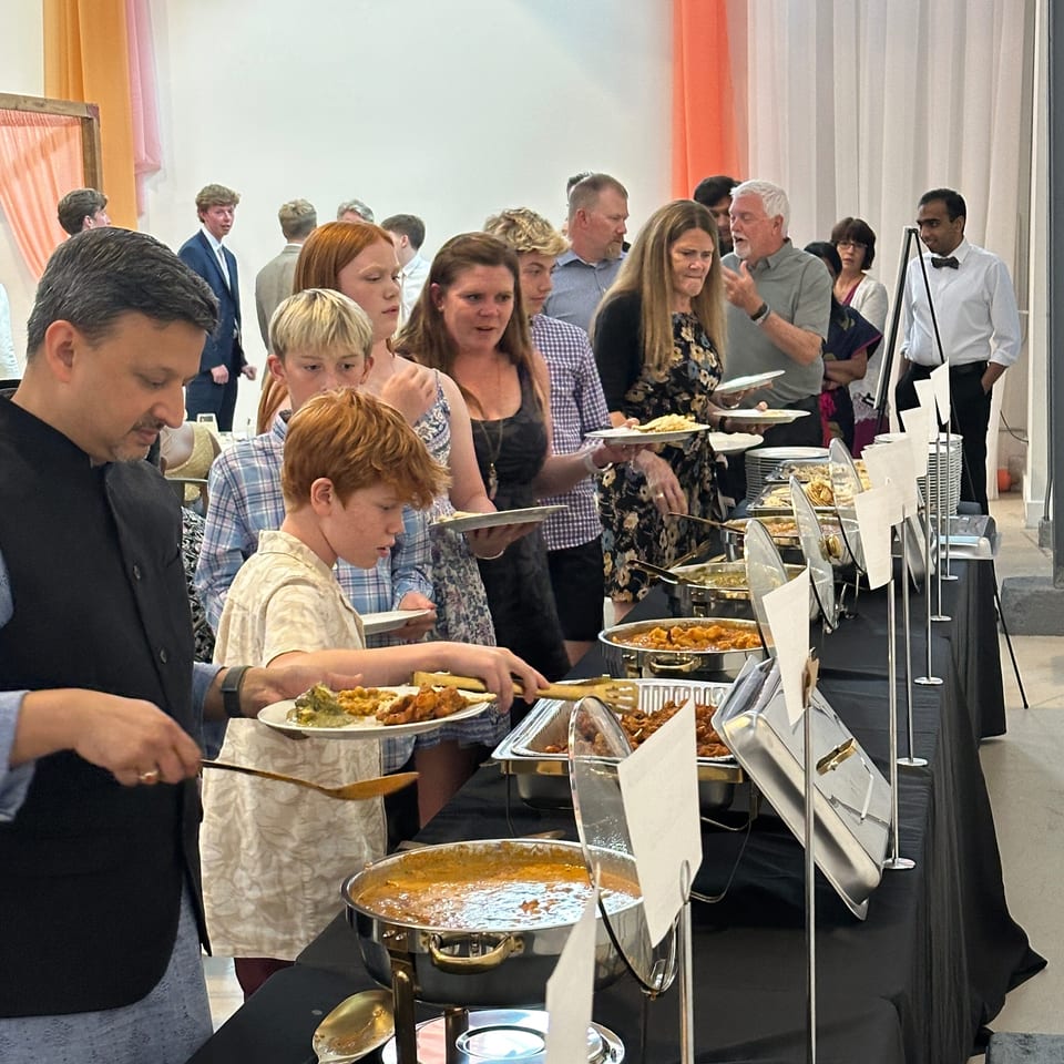 Guests serve themselves from a buffet of hot dishes in a brightly decorated dining room.